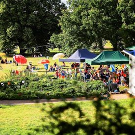 Scene from the radio play summer: Meadow with tents, colourful umbrellas and people; Photo: Tino Pfund